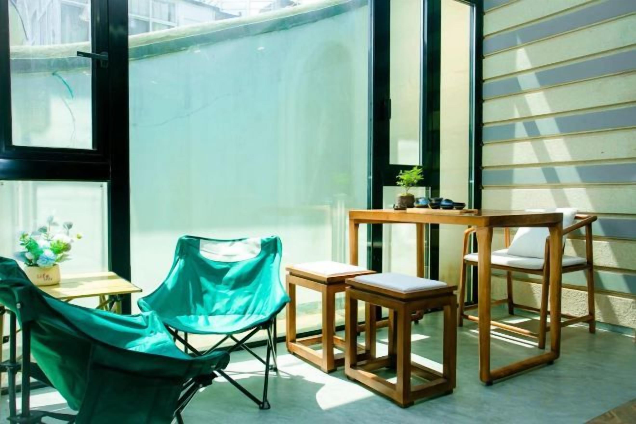 Una habitación con una silla verde, una mesa de madera y una planta pequeña.