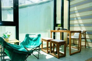 Une pièce avec une chaise verte, une table en bois et une petite plante.