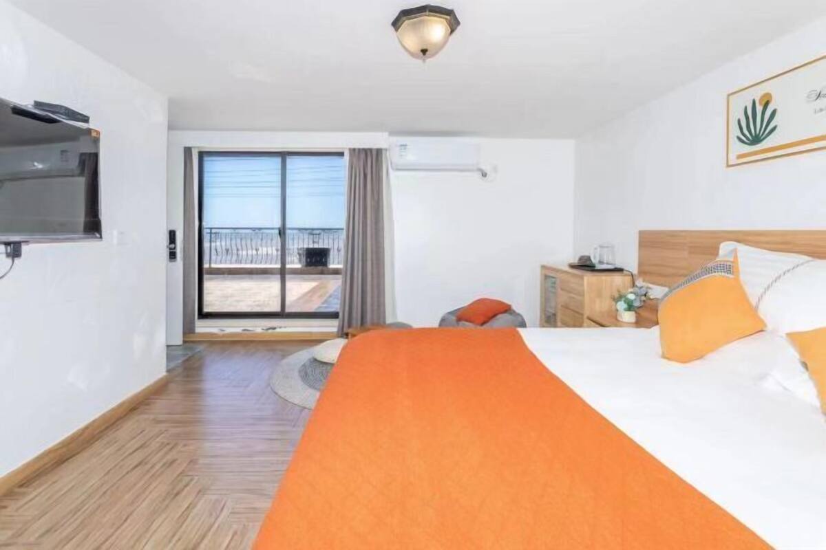 Une chambre d’hôtel avec un lit, une télévision, un bureau et un balcon offrant une vue.