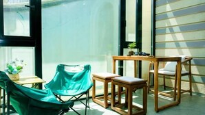 Une pièce avec une table et des chaises en bois, une chaise verte et une petite plante posée sur la table.
