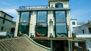 Un immeuble à plusieurs étages doté de grandes fenêtres, de climatiseurs et d’un balcon.