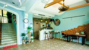 Une pièce spacieuse avec un sol à motifs, un escalier, un coin cuisine et une table à manger avec des chaises.