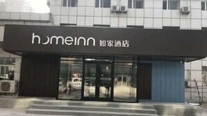 Un hotel con fachada moderna, destacando una señalización con el nombre 'homeinn' y caracteres chinos.
