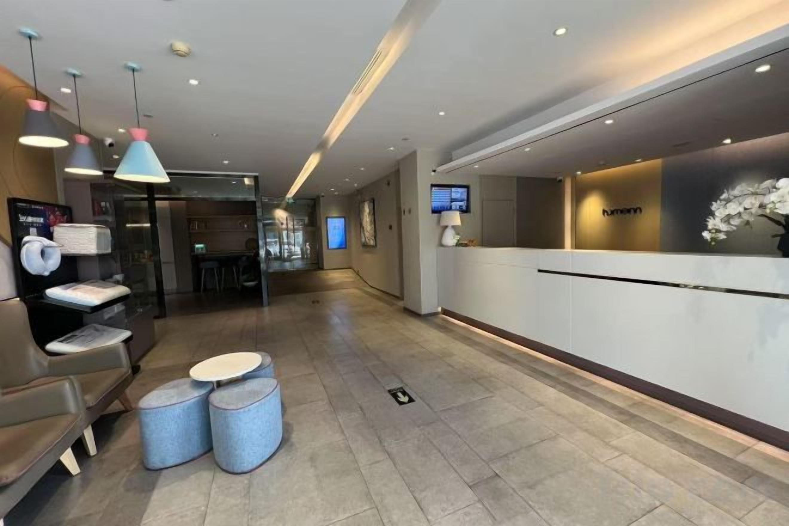 A hotel reception area with a reception desk, seating area, and a TV screen.