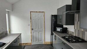 Une cuisine moderne dotée d’un four à micro-ondes encastré, d’une cuisinière et de meubles de rangement aux couleurs sombres.