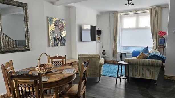 Un salon comprenant un coin repas, un canapé, un téléviseur et une fenêtre avec des rideaux.