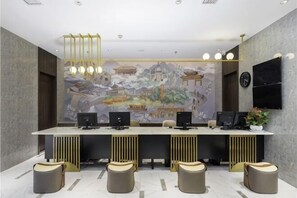 Zona de recepción con una larga barra de mostrador, múltiples monitores de computadora y un gran mural en la pared.