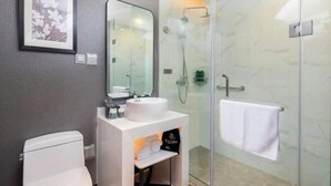 Une salle de bain moderne équipée de toilettes, d’un lavabo, d’un miroir et d’une douche.