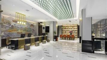A modern hotel lobby with a reception desk, seating area, and a decorative wall.