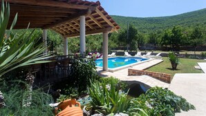 A pool area with a pergola, lounge chairs, and a view of a mountainous landscape. - Villa Bosnjak with a private pool (Osoje)