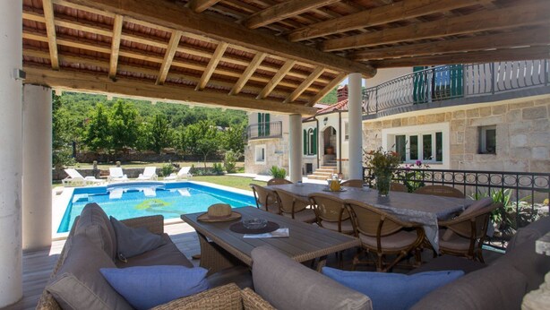 An outdoor patio with a pool, wicker furniture, and a stone building in the background. - Villa Bosnjak with a private pool (Osoje)