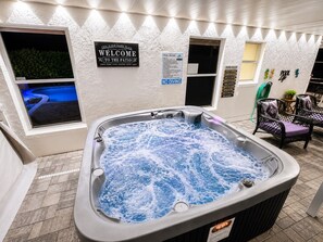 Een bubbelbad in een goed verlichte binnenterras, met een bordje dat gasten welkom heet.