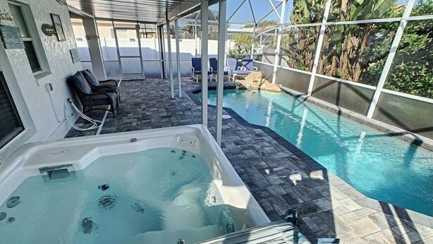 A hot tub and a pool area with lounge chairs and a covered patio. - 4m Disney : Private Pool, Hot Tub, Game Room & Fast WiFi, pets, Guests favorite (Kissimmee)