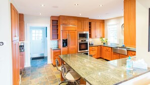 A modern kitchen with wooden cabinets, stainless steel appliances, and a granite countertop. - Magnificent Ocean View; Walk to beaches and town (Swampscott)