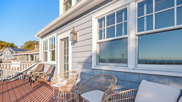 A deck with wicker chairs and a white sofa, overlooking a body of water. - Magnificent Ocean View; Walk to beaches and town (Swampscott)