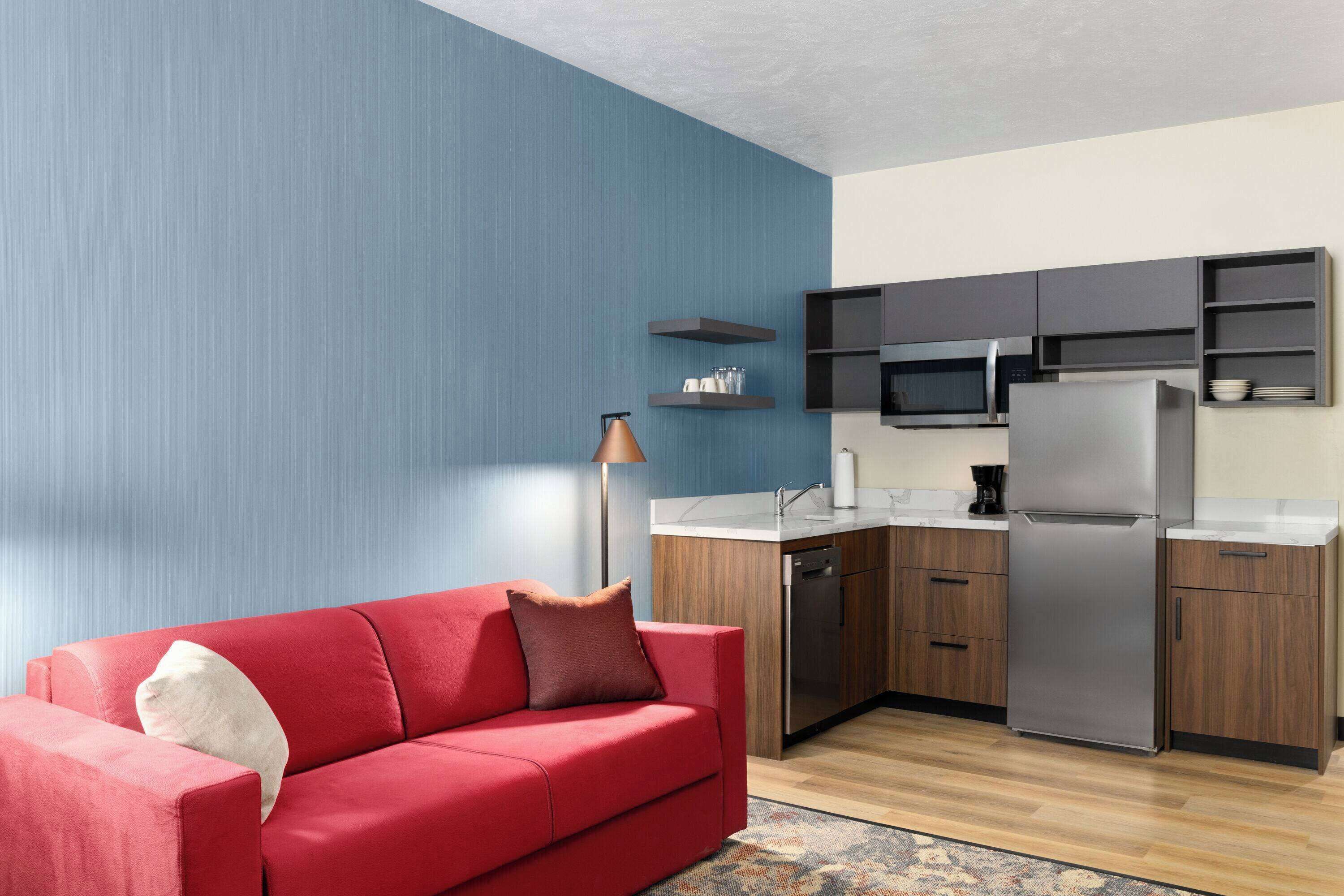 A modern kitchen with a red sofa, wooden cabinets, and a built-in microwave.