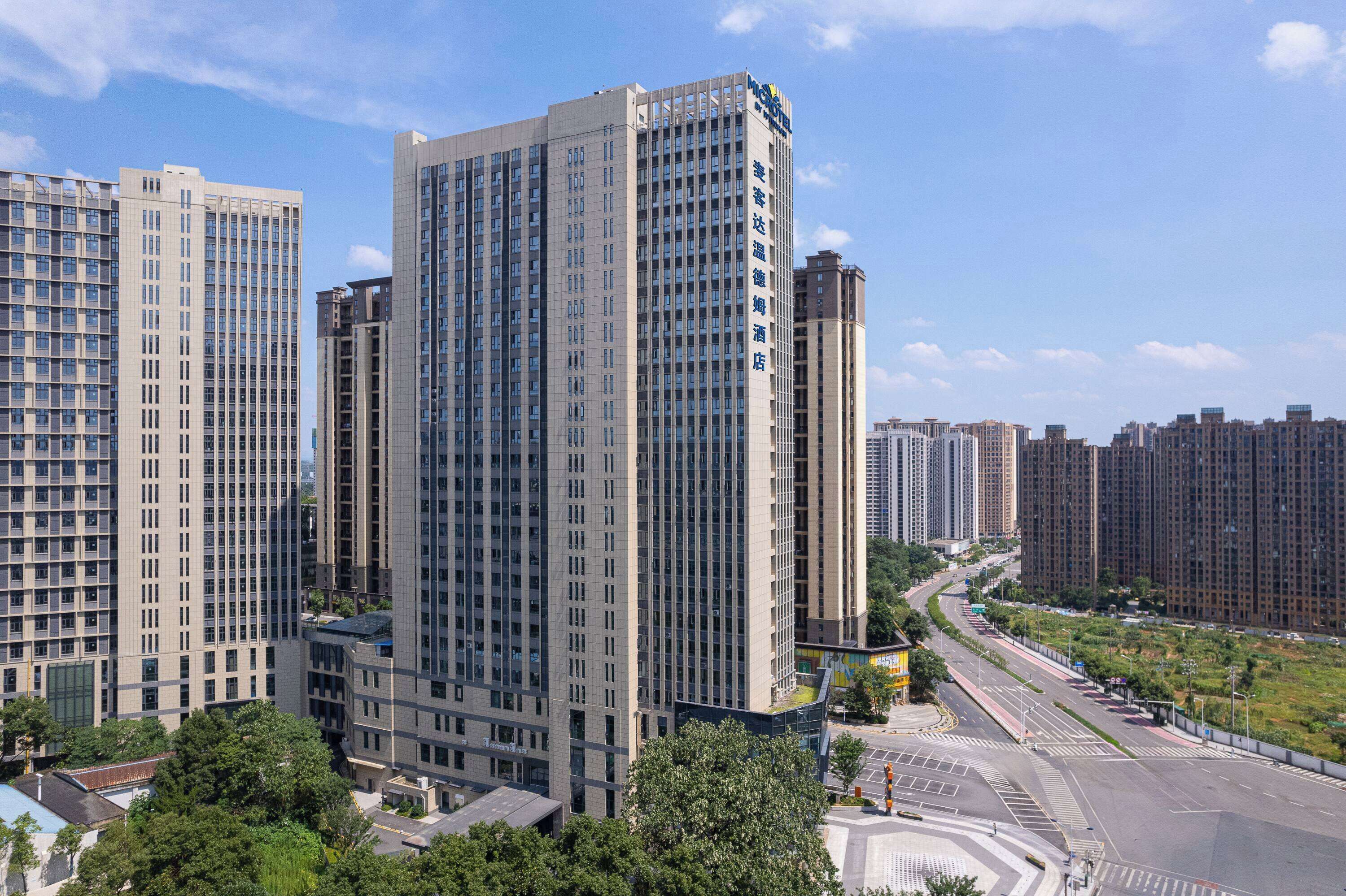 Un hôtel de grande hauteur, avec de nombreux étages, une entrée imposante et une vue sur les immeubles environnants.