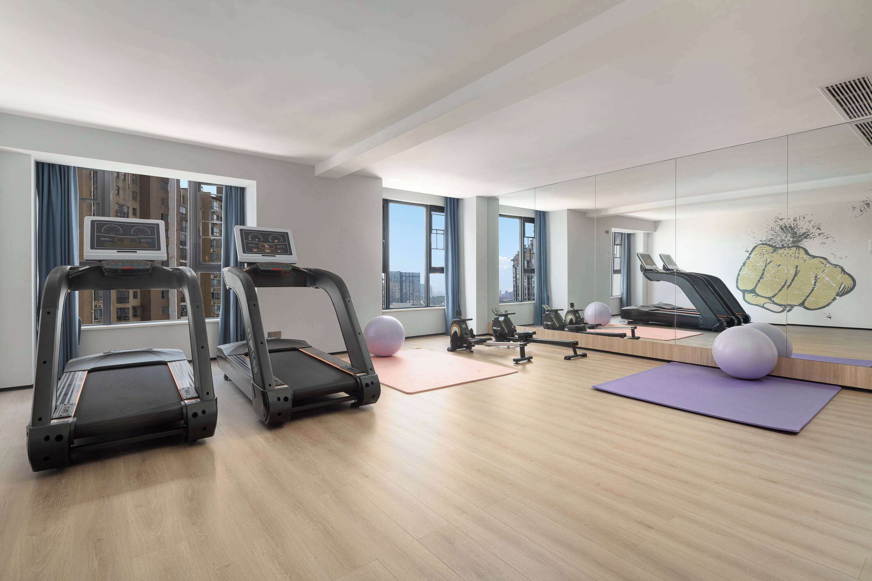 A modern gym with treadmills, exercise balls, and a large mirror.