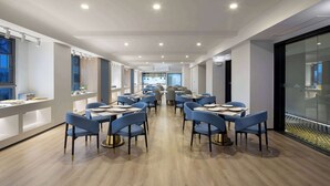 A modern dining area with blue chairs and tables, wooden flooring, and recessed ceiling lights. - Microtel By Wyndham Changsha South Railway Station (Changsha)