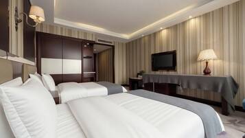A hotel room with two beds, a TV, a desk, and a lamp.