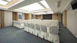 Un salón de conferencias con techo alto, tragaluces y filas de sillas blancas.