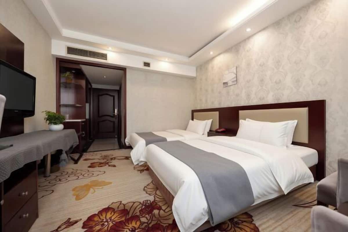 Una habitación de hotel con cama, escritorio, televisor y una puerta que da a otra habitación.