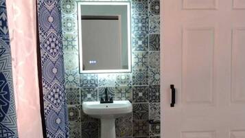 A bathroom with a white sink, patterned tiles, and a mirror.