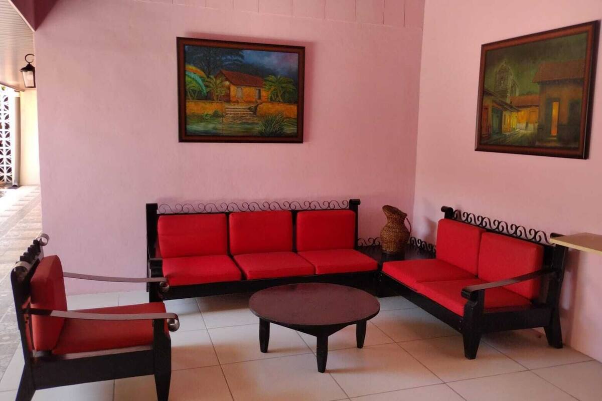 Une pièce comprenant un canapé rouge, une table basse et deux tableaux accrochés aux murs.