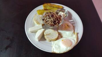 A plate with eggs, cheese, bread, and a small bowl of rice.