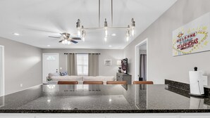 Eine moderne Küche mit Granit Arbeitsplatten, weißen Schränken und einem Deckenventilator.