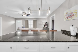 Una cocina moderna con encimeras de granito, muebles blancos y un ventilador de techo.