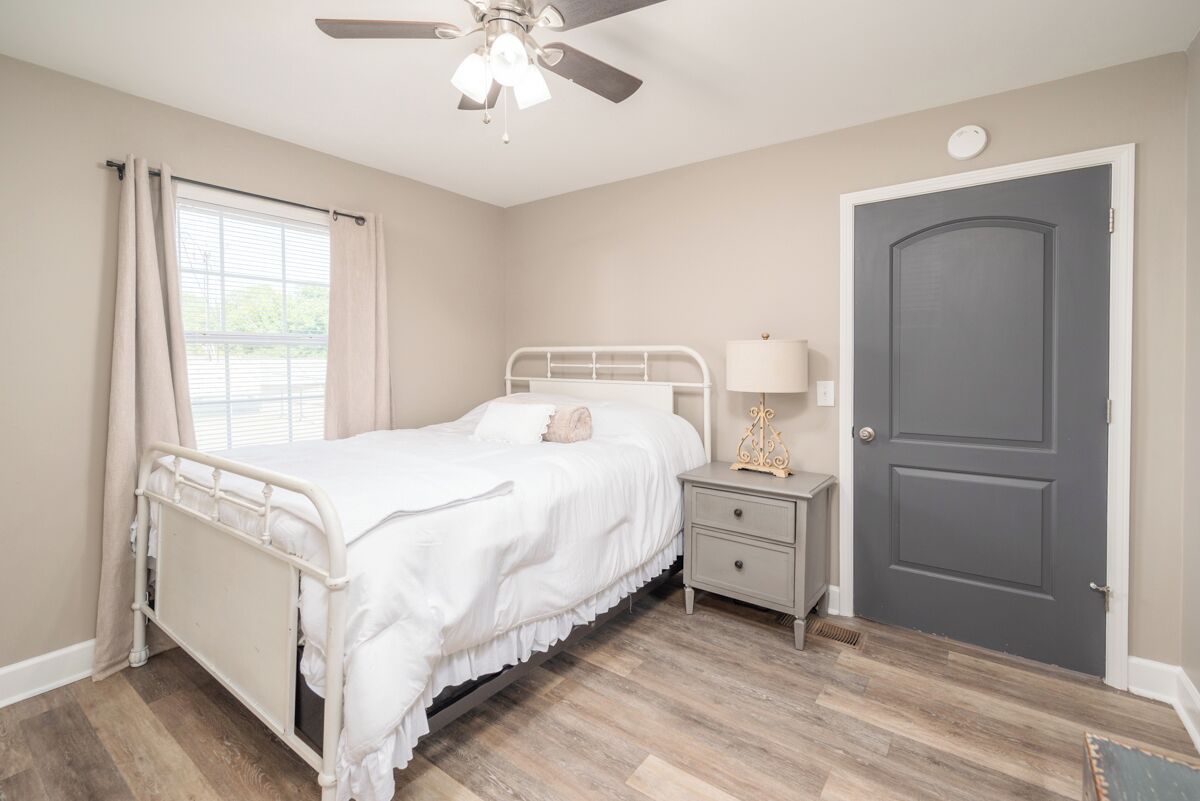 A bedroom with a bed, nightstand, lamp, and a door.