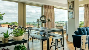 Una sala de estar moderna con comedor, ventanas grandes y vistas a la ciudad.