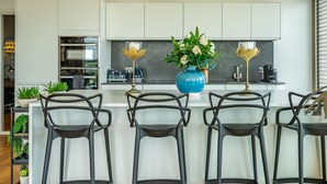 Una cocina moderna con armarios blancos, una isla central con taburetes de bar e iluminación decorativa.