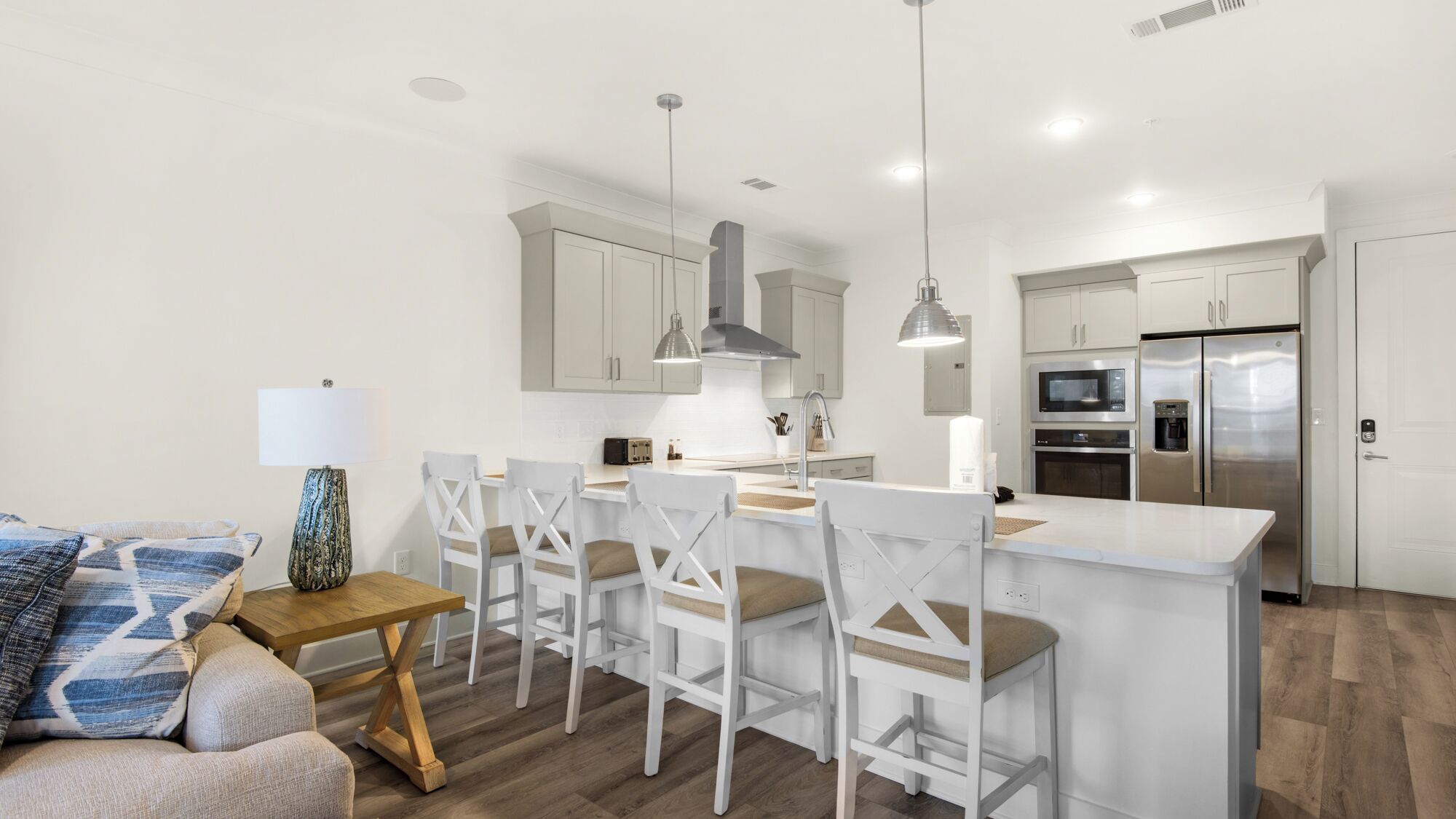 Una cocina moderna con armarios blancos, un refrigerador de acero inoxidable y una isla central con taburetes de bar.