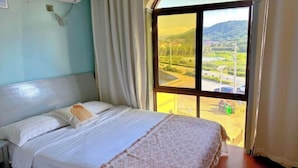 Een hotelkamer met een bed, een raam met uitzicht op het landschap en een airconditioning.