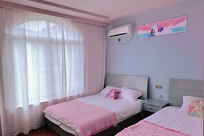 A bedroom with two beds, a window with sheer curtains, an air conditioning unit, and a wall with two framed pictures. - Qiaoyu Inn (Zhoushan)
