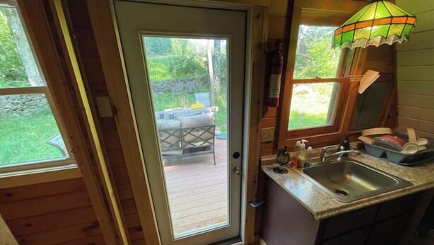 A wooden cabin with a glass door leading to an outdoor patio area.