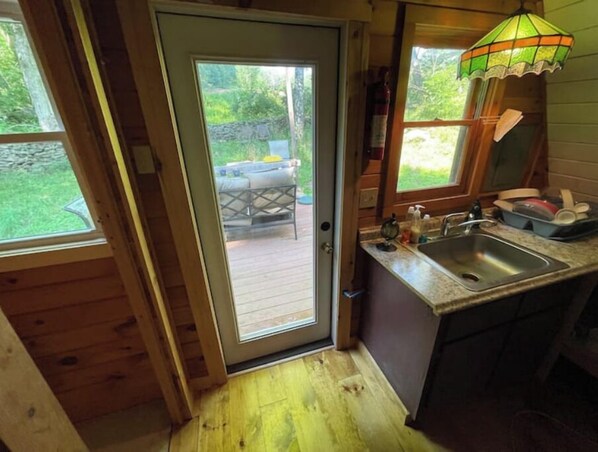 A wooden cabin with a glass door leading to an outdoor patio area.