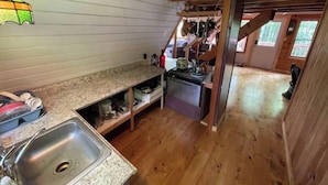 A compact kitchen with wooden floors, a granite countertop, and a stainless steel sink.
