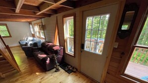 A cozy cabin interior with a wooden floor, a sofa, and a dog.