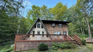 A cabin with a wooden deck, a staircase, and a fenced area.