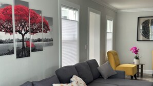 Una sala moderna con un sofá seccional gris, un sillón amarillo y una mesita con un jarrón de flores.