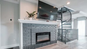Una sala de estar moderna con chimenea, un televisor de pantalla plana y una escalera en espiral.