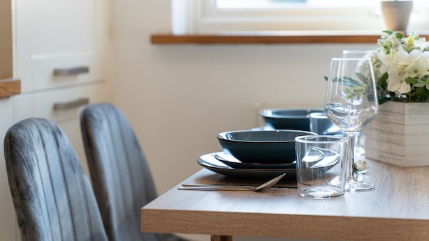 A dining table set with blue plates, clear glasses, and a small potted plant. - Open Mind Property - 4 Beds 2 Bathrooms & Parking (Portsmouth)