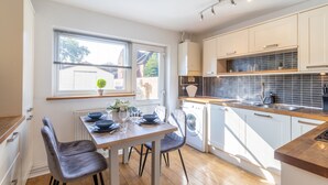 A modern kitchen with white cabinets, a wooden countertop, and a built-in washing machine. - Open Mind Property - 4 Beds 2 Bathrooms & Parking (Portsmouth)