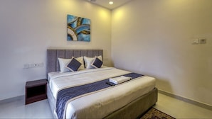 A bedroom with a bed, a ceiling fan, recessed lighting, a painting, and a nightstand. - Eco Stay Mount Road (Chennai)