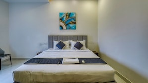 A modern bedroom with a large bed, a ceiling fan, and a wall-mounted abstract painting. - Eco Stay Mount Road (Chennai)