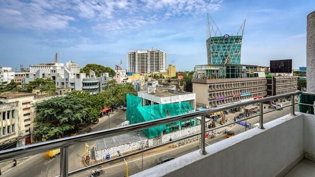 A cityscape with various buildings, including a construction site with green netting. - Eco Stay Mount Road (Chennai)