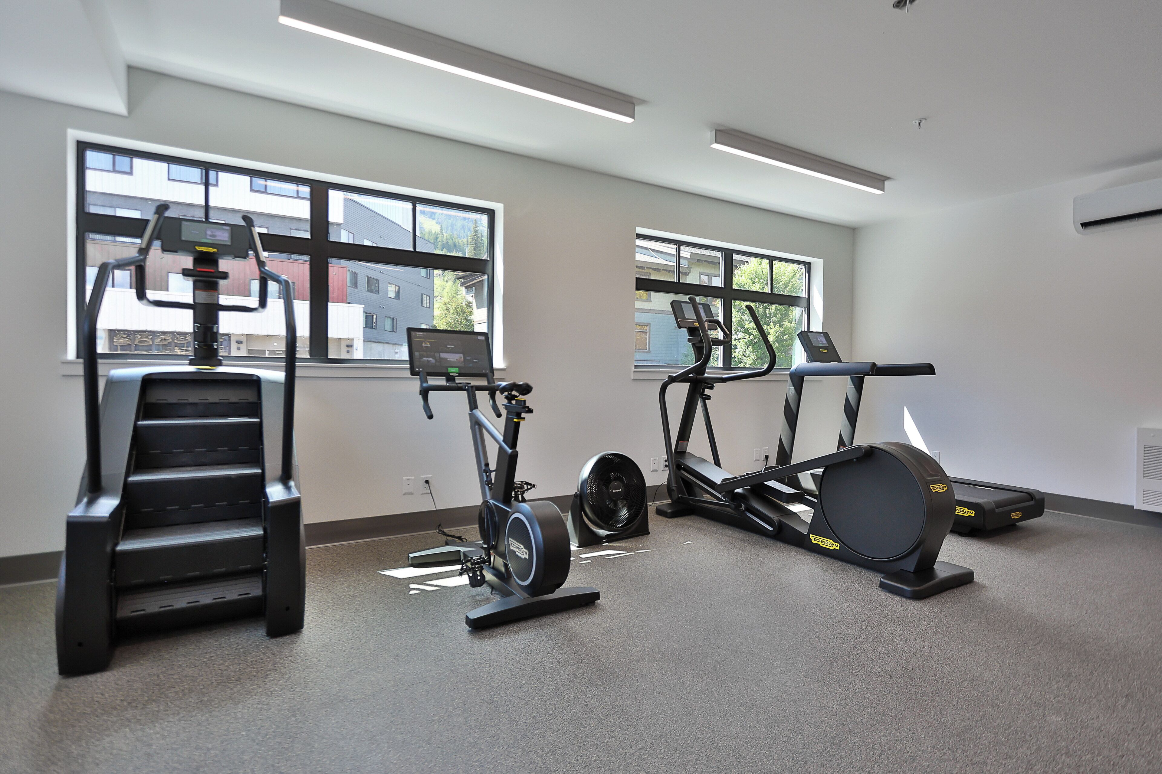 A gym with cardio machines, weight machines, and a treadmill.